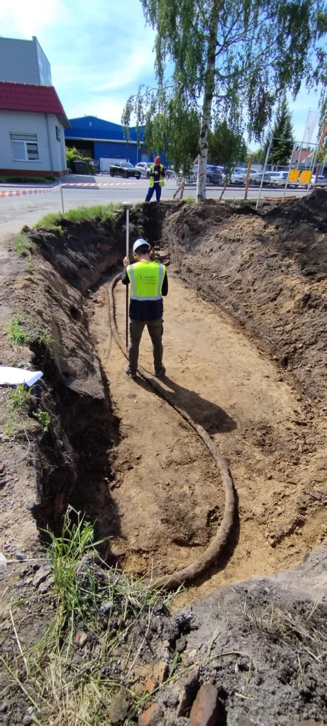 Układanie kabla energetycznego w wykopie liniowym - pracownik prowadzi kabel Instalacje elektryczne nN/SN - układanie kabla, Oława