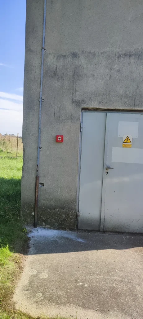 zdjęcie wieży energetycznej z zamontowanym wyłącznikiem alarmowym na ścianie zewnętrznej